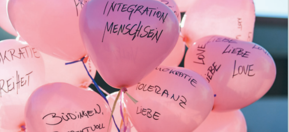 Luftballons mit Aufschriften wie "Integration, Menschsein"